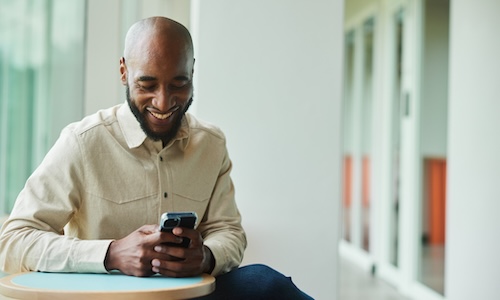 smiling man taking compliance training on his phone